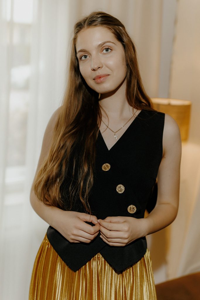 Set Teia – fustă plisată din catifea aurie și vestă din stofă neagră cu nasturi aurii, perfect pentru evenimente speciale și ținute versatile din Colecția toamnă-iarnă 2024.