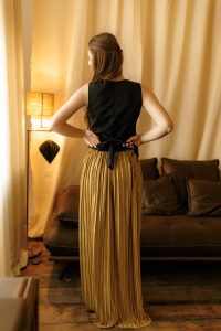 Set Teia – fustă plisată din catifea aurie și vestă din stofă neagră cu nasturi aurii, perfect pentru evenimente speciale și ținute versatile din Colecția toamnă-iarnă 2024.